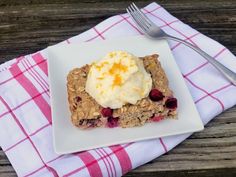 a white plate topped with granola and ice cream on top of a wooden table