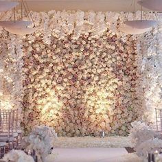 a wedding setup with white flowers on the wall and chandeliers hanging from the ceiling