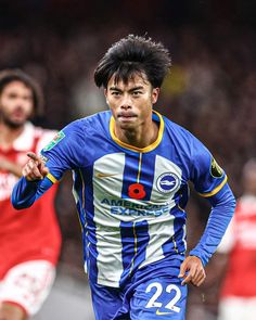 a soccer player running with the ball in his hand and two other players behind him