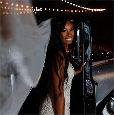 a woman in a wedding dress holding up a black suit case with her hand on the door