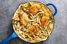 pasta with chicken, spinach and parmesan cheese in a blue dish on a gray surface