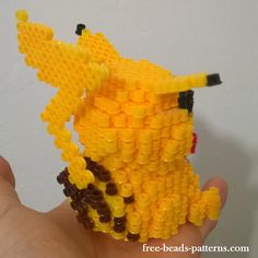 a hand is holding a lego model of a yellow dog made out of small beads