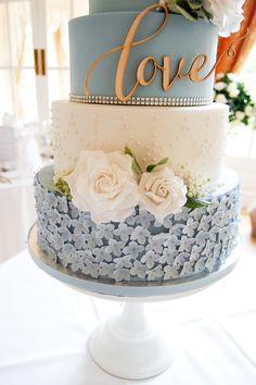 a blue and white wedding cake with flowers on top