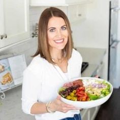 a woman holding a bowl of salad in her hands