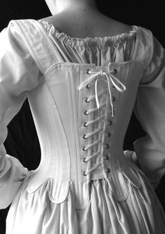 "This 18th century corset is rigidly boned with closely spaced 1/4\" steel bones and is cut to enhance and lift the bust, and shape the waist. The additional lacing up the center front allows for increased adjustment. The waist tabs, cut in one with the corset, curve and smooth over the hips. The over the shoulder straps adjust with a front tie and are basted in at the back. The straps are easily removable. Strapless stays are one of the signature looks of this period. Features include: Ø Side s Elegant Historical Design Corset For Costume, Elegant Historical Design Corset For Costume Party, Elegant Corset With Historical Design For Costume Party, Elegant Costume Corset With Boning, Elegant Boned Corset For Costume, Elegant Boning Corset For Costume, Medieval Style Corset Back Wedding Dress, Medieval Corset Back Dress For Wedding, Medieval Corset Dress For Wedding