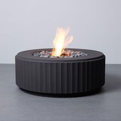 an outdoor fire pit with rocks on the bottom and flames coming out of it's sides