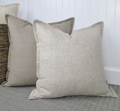 two pillows sitting on top of a bed next to each other in front of a white wall