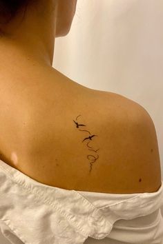 the back of a woman's shoulder with a bird tattoo on her left arm