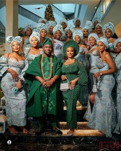 a group of women standing next to each other in green dresses and turbans