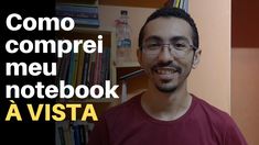 a man with glasses and a beard smiles in front of a book shelf filled with books