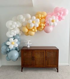 balloons are hanging on the wall next to a wooden cabinet and sideboard in a room