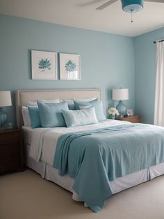 a bedroom with blue walls and white bedding in the center, along with two framed pictures on the wall