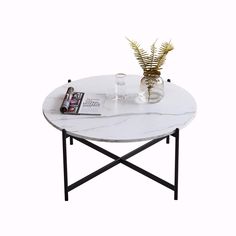 a white marble coffee table with black metal legs and a plant in a glass vase on top