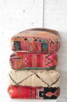 three colorful pillows stacked on top of each other in front of a white brick wall