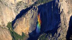 a rainbow in the middle of a mountain with water coming from it's side