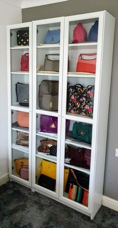 a white bookcase filled with lots of purses