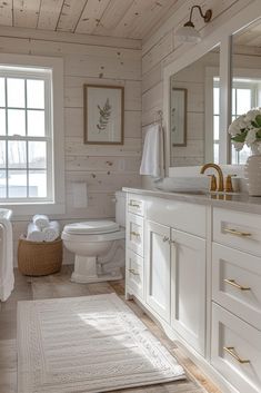 a white bathroom with wood paneling and gold handles on the sink, toilet and bathtub