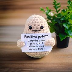 a crocheted stuffed animal holding a sign that says, positive potato i may be a tiny potato but i believe in you go do your thing