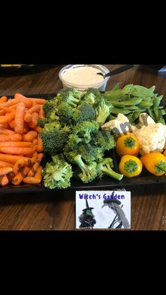 a tray filled with carrots, broccoli and other veggies on a table