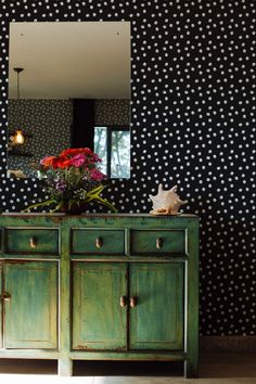 a green dresser sitting in front of a wall with black and white polka dots on it