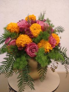 a vase filled with yellow and pink flowers on top of a table