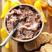 a bowl filled with dip surrounded by crackers and oranges