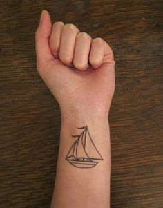 a hand with a small sailboat tattoo on it's left arm and wrist