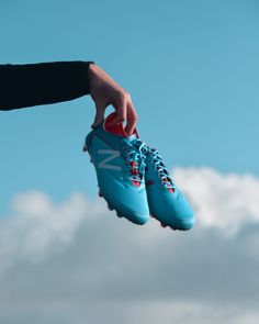 a pair of blue shoes being held up in the air