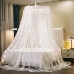 a canopy bed with white netting and fairy lights