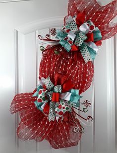 two red mesh wreaths with bows hanging on the front door, decorated with candy canes