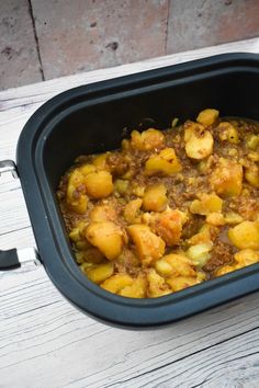 a casserole dish with potatoes and meat in it sitting on a wooden table