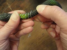 two hands are holding an object in the shape of a snake