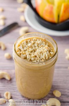 a jar filled with peanut butter sitting on top of a table next to an apple