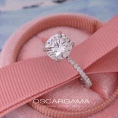 a diamond ring with a pink ribbon around it