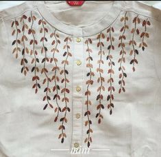 an embroidered white shirt with brown leaves on the front and back, along with gold buttons