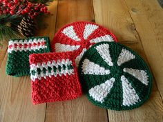 three crocheted christmas coasters sitting on top of a wooden table next to a pine cone