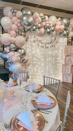 a table is set with silver and pink balloons