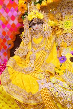 a woman dressed in yellow sitting on top of a bench next to flowers and decorations