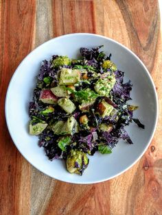 a white bowl filled with salad on top of a wooden table