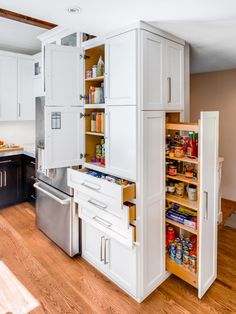 an open pantry in the middle of a kitchen with white cabinets and drawers on both sides