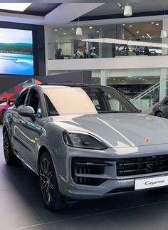 two porsche cayens are on display in a showroom, one is silver and the other is red