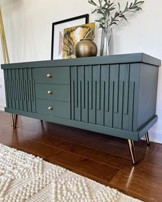 a green dresser with gold handles and drawers on it's sides in a living room