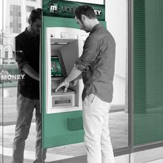 two men are looking at an atm machine