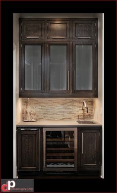 a kitchen with dark wood cabinets and white counter tops, along with a wine cooler