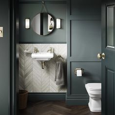 a white toilet sitting next to a bathroom sink under a round mirror on a wall