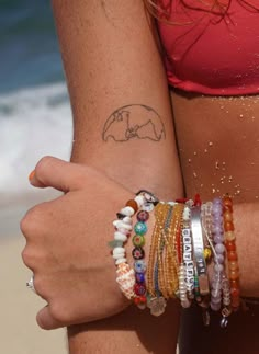 two women with bracelets on their arms near the ocean and sand in front of them