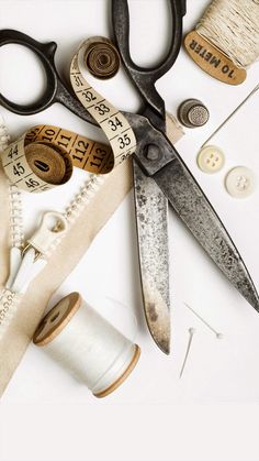 scissors, measuring tape, and other sewing supplies on a table with thread spools