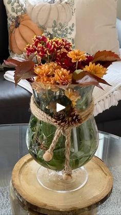 a glass vase filled with flowers sitting on top of a wooden table next to a couch