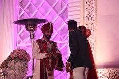 a man and woman standing next to each other in front of a purple lit room