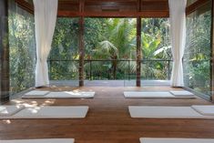 yoga mats are lined up on the floor in front of an open room with large windows